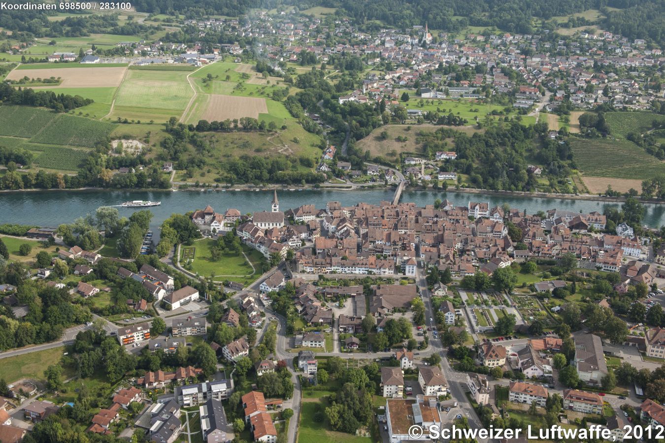 Diessenhofen (Position: 2'698'508.56, 1'283'148.38). Altstadt in der Bildmitt. Gedeckte 'Laag'-Holzbrücke über den Rein nach dem deutschen Gailingen. Links der Stadtkirche Diessenhofen: 'Unterhof'. Grosses Gebäude rechts (am Rhein): 'Oberhof'.